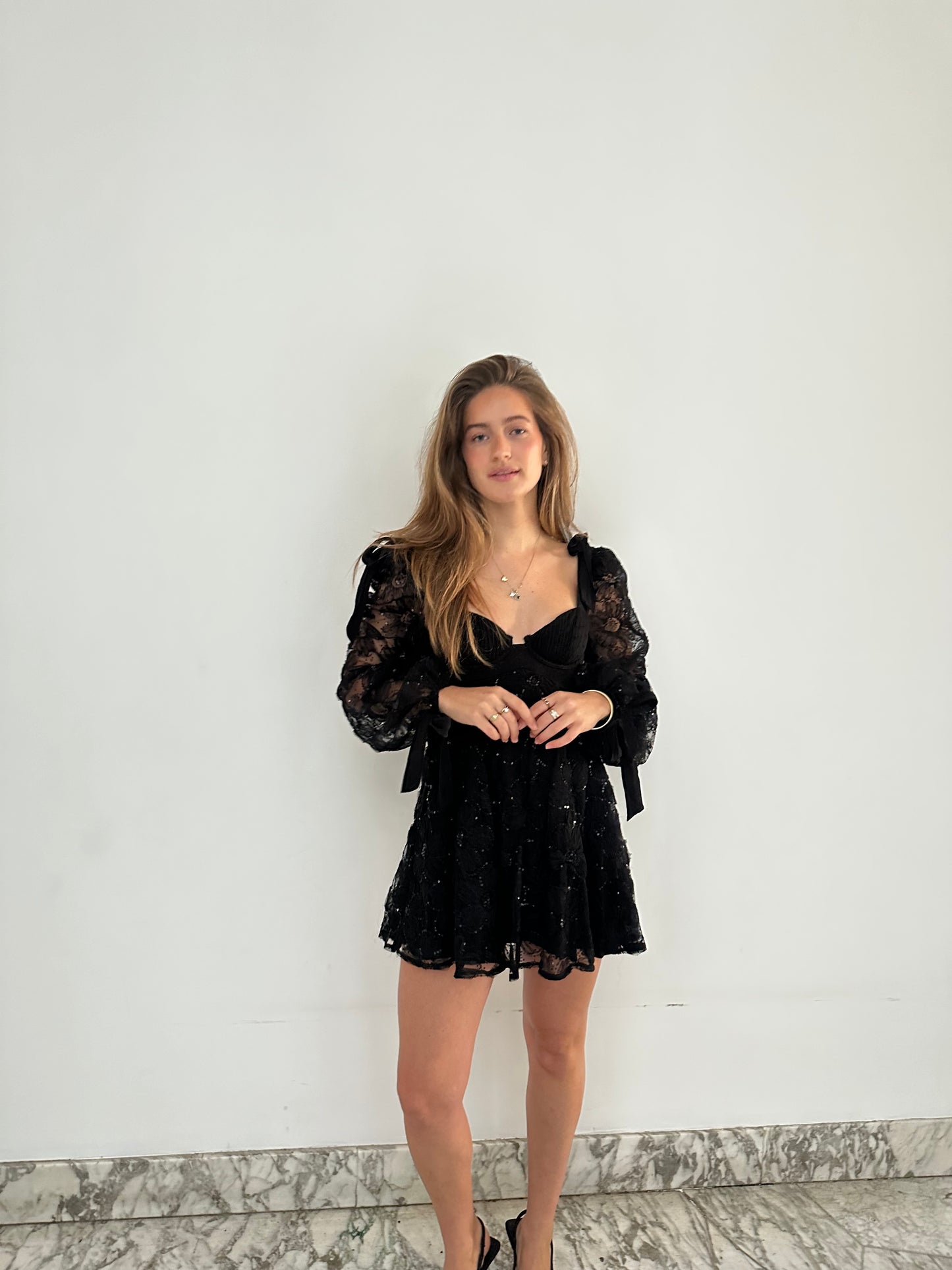 Kiersten Mini van For Love & Lemons - zwarte kanten mini-jurk met transparante mouwen te huur bij POOMBIES, jurk huren voor gala of feest