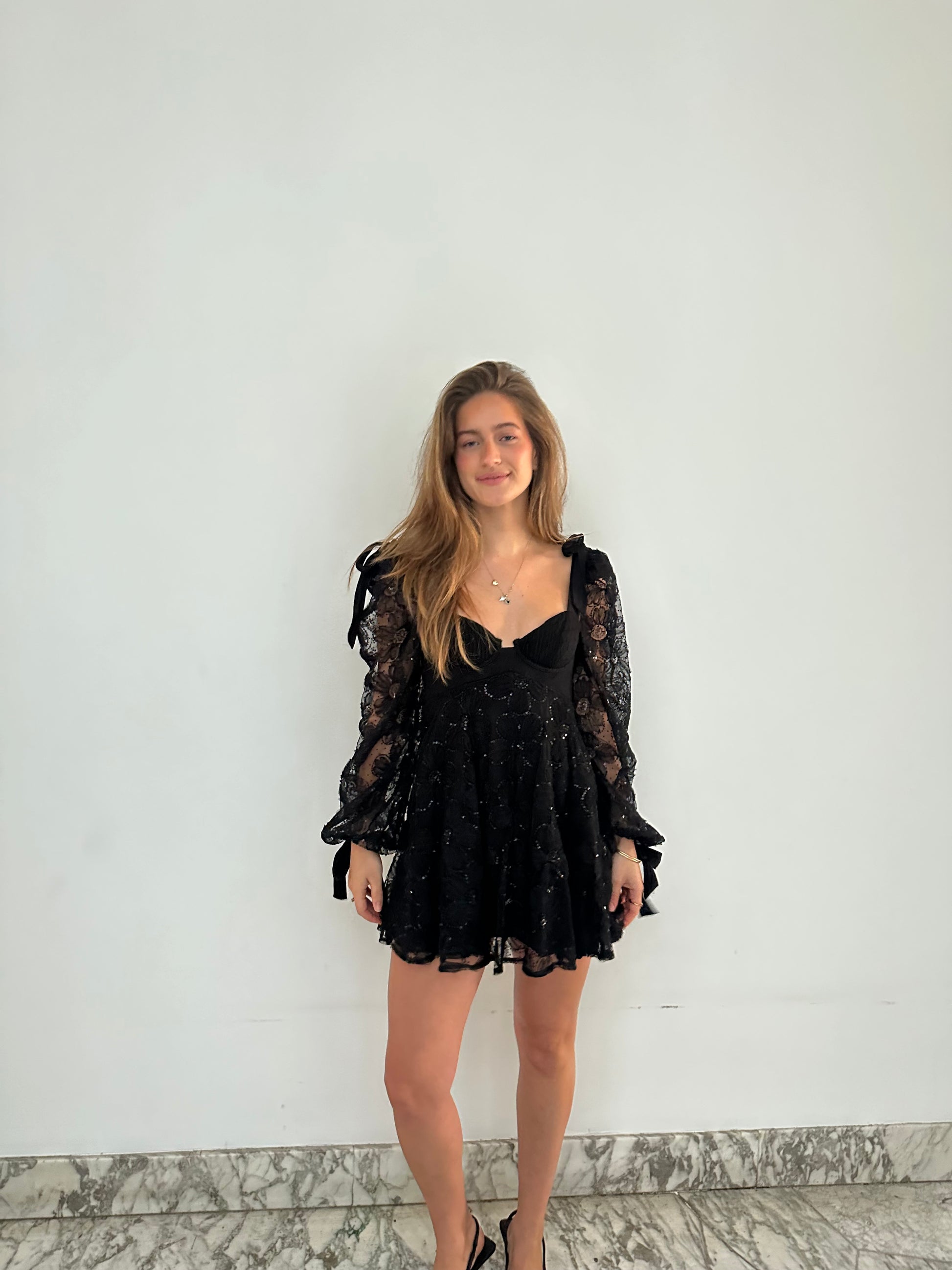 Kiersten Mini van For Love & Lemons - zwarte kanten mini-jurk met transparante mouwen te huur bij POOMBIES, jurk huren voor gala of feest